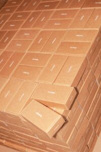 A person carefully packing a cardboard box with protective foam and sealing it with tape.