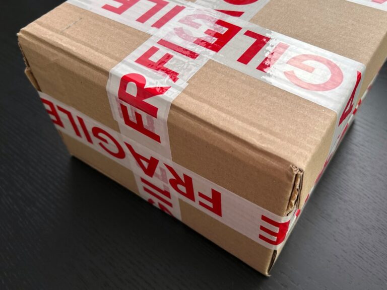 A close-up of hands assembling a cardboard shipping box on a table with packing materials.