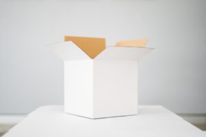 Three cardboard boxes of different thicknesses stacked on a wooden table with visible layered edges.