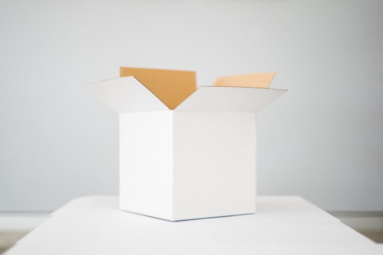 Three cardboard boxes of different thicknesses stacked on a wooden table with visible layered edges.