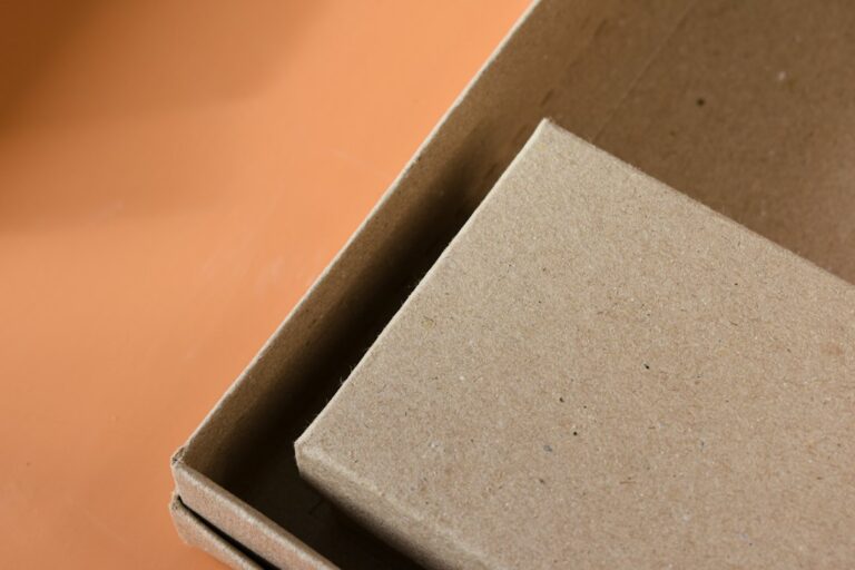 Workers place foam inserts around a precision component inside a corrugated shipping container.